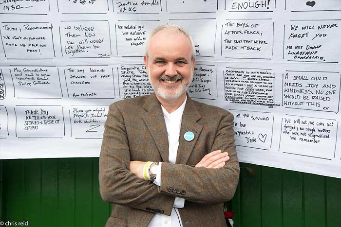Fig.27 Colm O'Gorman outside the entrance to the Monastery of the Sisters of Charity of Refuge Convent. 
Behind him is one of the sheets upon which participants on the parade wrote messages of support and solidarity.